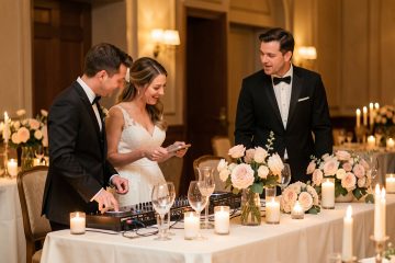 Un couple de mariés échange avec un DJ de mariage près d’une table élégamment décorée, dans une ambiance chaleureuse et raffinée.